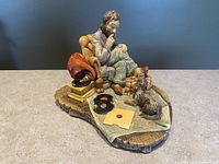 Front and side view of Naturecraft figurine showing man seated in armchair with dog and gramophone on detailed base.