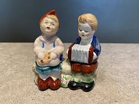 Front view showing detailed painting of boy playing accordion and girl holding sheet music figurine.