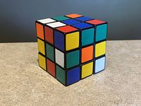 Front angled view of the Rubik's Cube showing multiple colored stickers including white, green, orange, blue, yellow, and red sides.