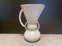 Front view of the off-white Beswick thistle jug showing fluted top and handle detail.