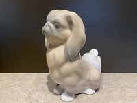Side view of the Lladro porcelain sitting Pekingese dog figurine highlighting its profile, coat details, and curled tail.