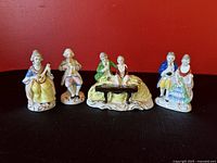 Front view of the set of four Occupied Japan porcelain figurines portraying a musical and social gathering, showing detailed multicolor handpainting and period costumes.