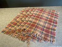 Set of 5 handwoven vintage placemats arranged on a countertop, showing the plaid multicolor pattern and fringed edges.