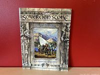 Front cover of the Sovereign Stone Game System RPG book showing fantasy characters and ornate border design.