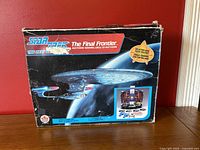 Photo of outer box showing Star Trek USS Enterprise starship with the game title and branding, box shows wear and damage.