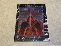Front cover of 'The Ashen Knight' sourcebook featuring a knight in red cloak holding a sword, with detailed background art.