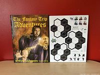 Front view of The Fantasy Trip Adventures hardcover book and hex tile punch-out sheet, displayed against a red background.