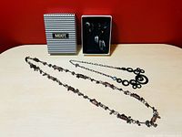 Four necklaces including one boxed necklace and earring set, displayed on a table with red background.