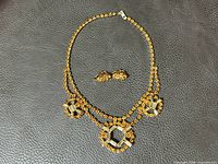Full view of vintage amber rhinestone necklace and matching earrings laid out on dark textured surface.
