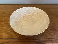 Top view of cream lustre ceramic bowl with faux wood grain texture on the interior surface.