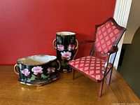 Front view of the vintage ceramic floral planter and vase with the miniature planter chair beside them. Shows the floral designs, gold-colored handles, and old repair on planter.