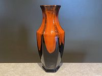 Front view of the vase showing the orange and black fat lava drip glaze with hexagonal base and flared rim.