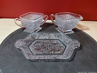 Three-piece set including a handled sugar bowl, creamer, and hexagonal tray featuring floral and dot pressed glass pattern.
