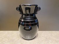 Front view of vintage L.E. Smith black amethyst Grecian double ear vase with silver overlay decoration placed on a beige surface against neutral background.