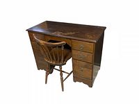Photo of vintage 1940s wooden kneehole desk with six drawers and brass Chippendale-style pulls alongside matching spindle-back chair, showing the wood finish and overall shape.