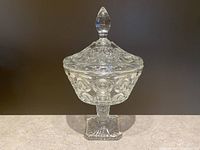 Front view of the vintage pressed glass candy jar showing the raised circle pattern on the bowl and the faceted finial on the lid.