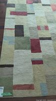 Rug laid out on hardwood floor showing full geometric block pattern and color palette.
