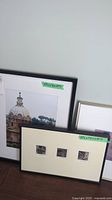 Photo showing three frames closely grouped, including a photographic print of a domed building and a framed triptych of small sketches.