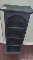 Front view of the black wooden bookcase with fixed shelves and decorative arch top