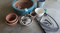 Various gardening pots including large turquoise ceramic pot, several terracotta pots, metal bucket, small basket with decorations, metal hanging brackets and accessories.