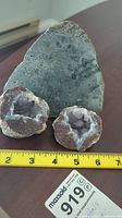 Photo showing two small geodes and one large flat stone with ruler for scale.