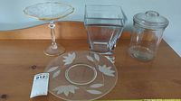 Glass pedestal plate, glass cookie jar with lid, square glass bowl, and octagonal glass bowl