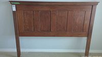 Full view of the wooden queen size headboard showing paneled design and wood finish.