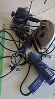 Top view of four power tools: sander, circular saw (Ryobi), electric drill, and heat tool with power cords