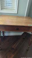 Photo showing front of wooden vintage table with drawer and marks on table top.
