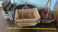 Wicker baskets and box of picture frames arranged on floor, with measuring tapes showing scale.