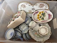 Bin of assorted Asian themed china pieces including cups, bowls, plates, and a rectangular serving tray