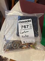 Image of assorted costume jewelry pieces in plastic bag with auction label