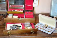 Wide view of wooden jewelry box with multiple compartments filled with assorted costume earrings in different styles and materials.