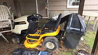 Side profile of mower with grass catcher under covered porch