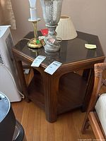 Front view of hexagon shaped wood end table with glass top and displayed lamps and lampshade