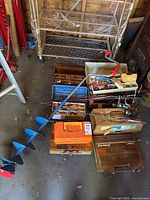 Overview photo showing fishing rods, tackle boxes, and hand auger on floor of shed