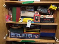 Shelf of assorted boxed games including Star Trek: The Game, Four Letter Words, Trivia Cards, and others