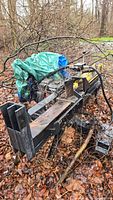 Overall angled view of log splitter showing beam, wedge, frame, and green tarp.
