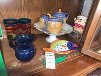 Overview of the lot showing colorful ringed glasses, blue pitcher, cream and sugar lusterware, cake plate, fish dish, and cookie jar.