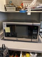 Full view of the Oster stainless steel microwave oven on the kitchen counter, showing its size and condition.