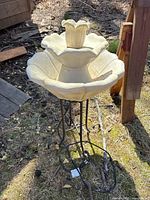 Overall view of the outdoor garden fountain showing the flower-shaped design on a metal stand outdoors.