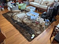 Full view of the brown and tan shag style rug with household items on top, showing thick pile and pattern.