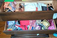 Open drawer showing various colorful scarves, hosiery packages, and assorted fabric bags including makeup and jewelry bags.