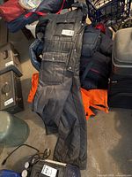 Northern Summit one-piece black snowsuit size L laid out on the floor showing front zipper and snap buttons