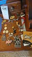Overview of assortment of animal-themed jewelry and collectibles on wooden surface, including keychains, pins, and charms