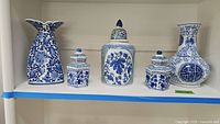 Front view of all five blue and white porcelain Asian style vases and ginger jars on shelf