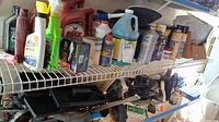 Shelf with assorted car care chemical bottles including motor oil, polishes, and cleaning sprays.