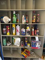 Shelving unit holding assorted cleaning and maintenance supplies including spray bottles, tubes, and liquid containers in plastic and metal packaging. Includes Murphy Oil Soap and WD-40 cans.