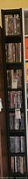 Full view of tall black shelving unit filled with DVDs arranged vertically in multiple rows.