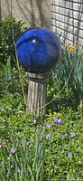 Blue glass gazing ball on stone pedestal in garden
